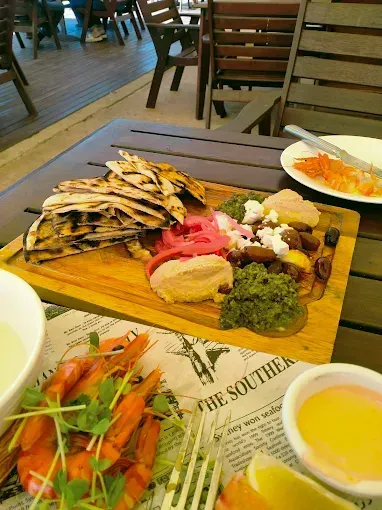 Wooden board with hummus, pita bread, and shrimp — The Beach Bar and Restaurant at Montes in Cape Gloucester, QLD