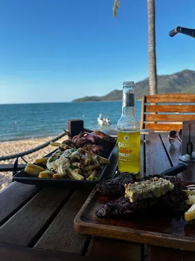 Steak and fries with a beer on a beachfront table — The Beach Bar and Restaurant at Montes in Cape Gloucester, QLD