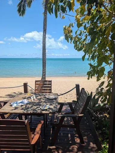 Beachfront dining area with table and chairs — The Beach Bar and Restaurant at Montes in Cape Gloucester, QLD