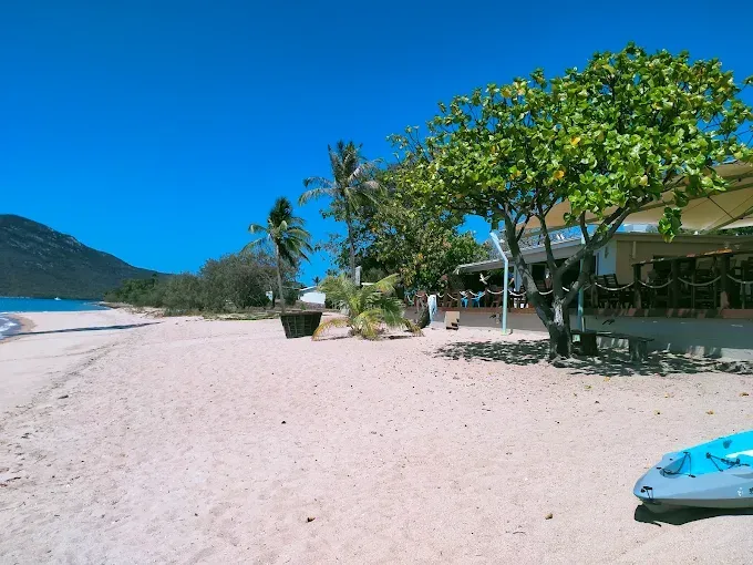 Beach with turquoise water, trees, and a building — The Beach Bar and Restaurant at Montes in Cape Gloucester, QLD
