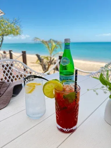 Cocktails and water bottle on white table overlooking beach — The Beach Bar and Restaurant at Montes in Cape Gloucester, QLD