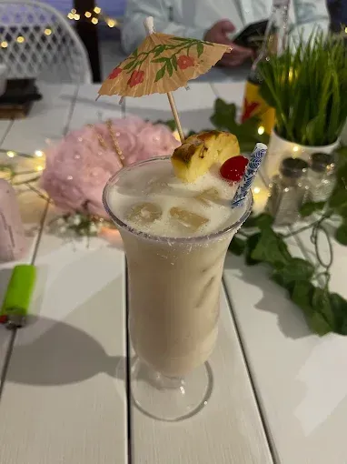 A garnished cocktail with an umbrella on a white table — The Beach Bar and Restaurant at Montes in Cape Gloucester, QLD