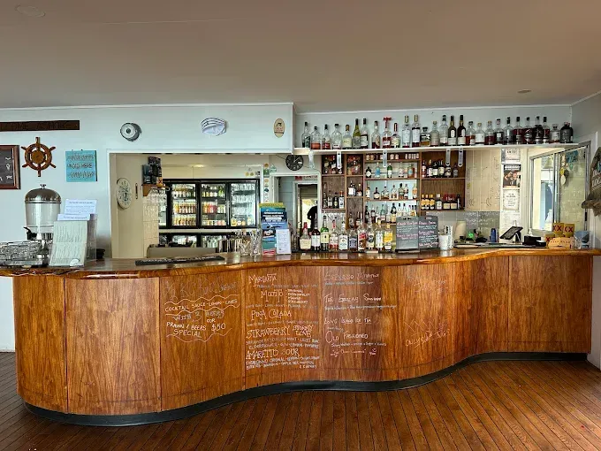 A wooden bar with drinks, bottles, and a menu — The Beach Bar and Restaurant at Montes in Cape Gloucester, QLD