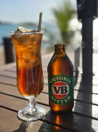 Tall glass drink and a bottle of Victoria Bitter — The Beach Bar and Restaurant at Montes in Cape Gloucester, QLD