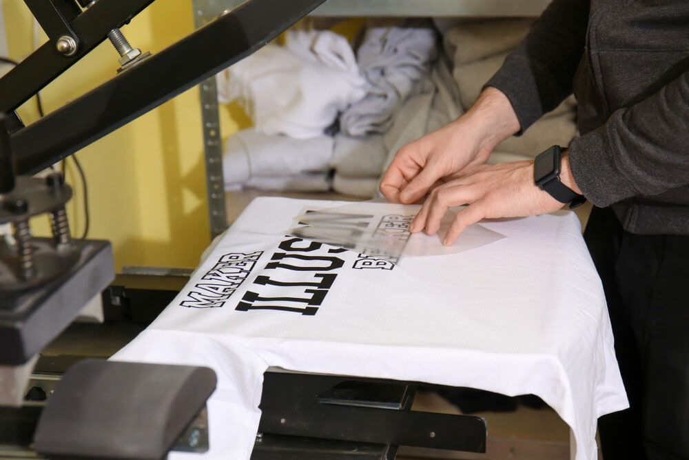 Person Aligns a Printed Design on a White T-shirt — DXMA Designs In Campbelltown, NSW