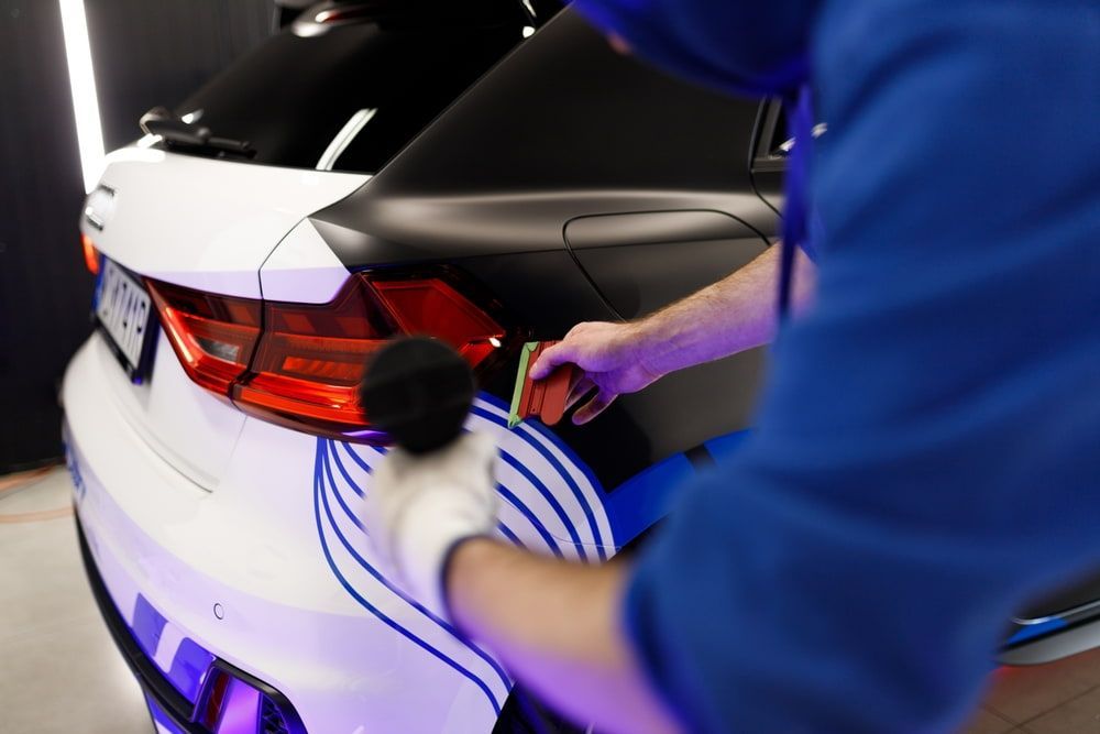 Man Applying A Vinyl Wrap to a Car Door — DXMA Designs In Wollongong, NSW