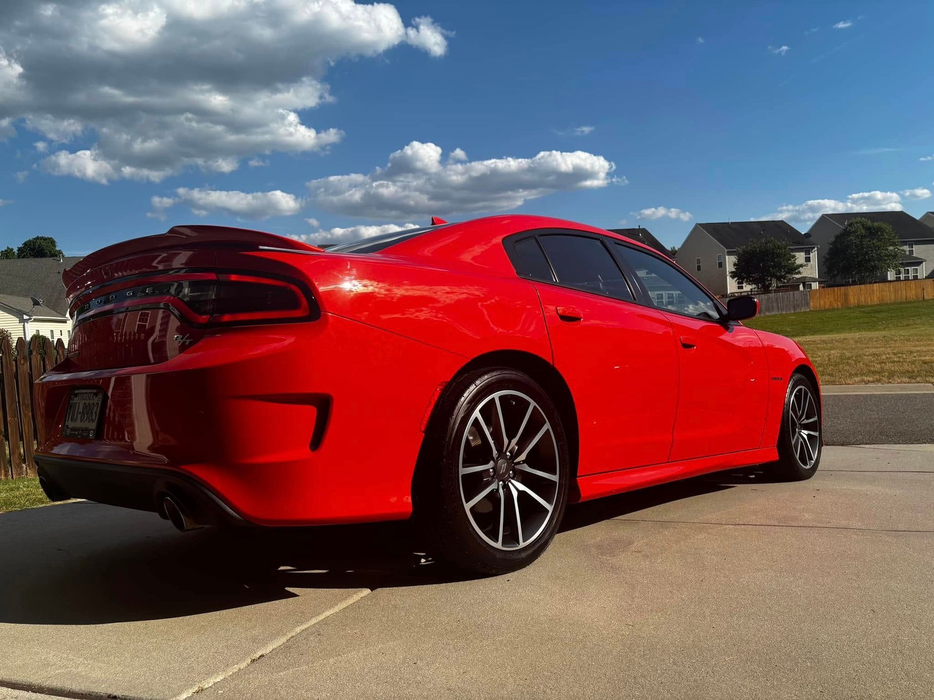 Red Dodge Charger parked on a driveway, bright sunny day.