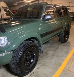 Green Toyota Land Cruiser SUV with black wheels parked in a garage.