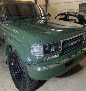 Green Toyota Land Cruiser with black wheels parked in a garage.