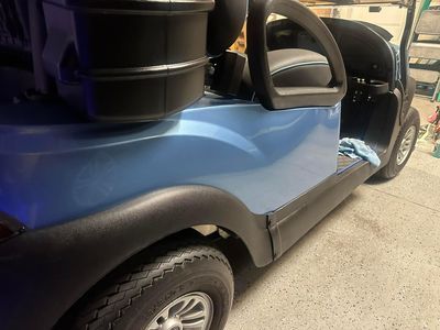 Blue golf cart with black trim, parked inside a garage.