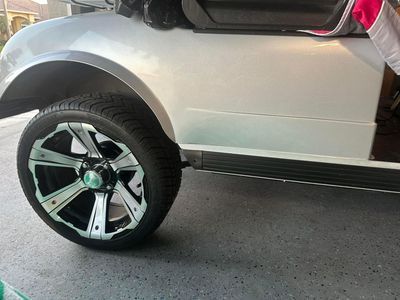 White golf cart with a black and silver rim on the front tire.