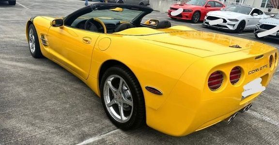 Yellow Corvette convertible parked on pavement.