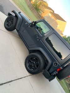 Black Jeep Wrangler parked on a driveway with black rims.