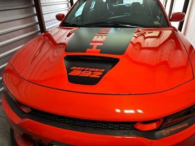 Bright red Dodge Charger with black racing stripes and