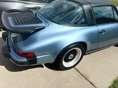 Blue Porsche 911 Targa with black roof and spoiler, parked on a driveway.