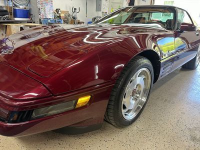 Maroon C4 Corvette, shiny paint, low angle, parked indoors.