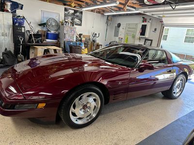 Burgundy Corvette in a garage; silver wheels, dark interior, garage setting.