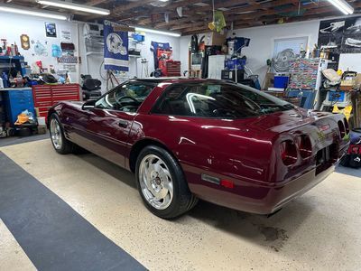 Maroon Corvette coupe parked inside a garage.