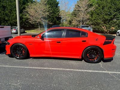 Red Dodge Charger with black rims parked in a parking lot.