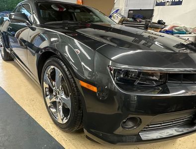 Dark gray Camaro with chrome wheels, parked in a garage.