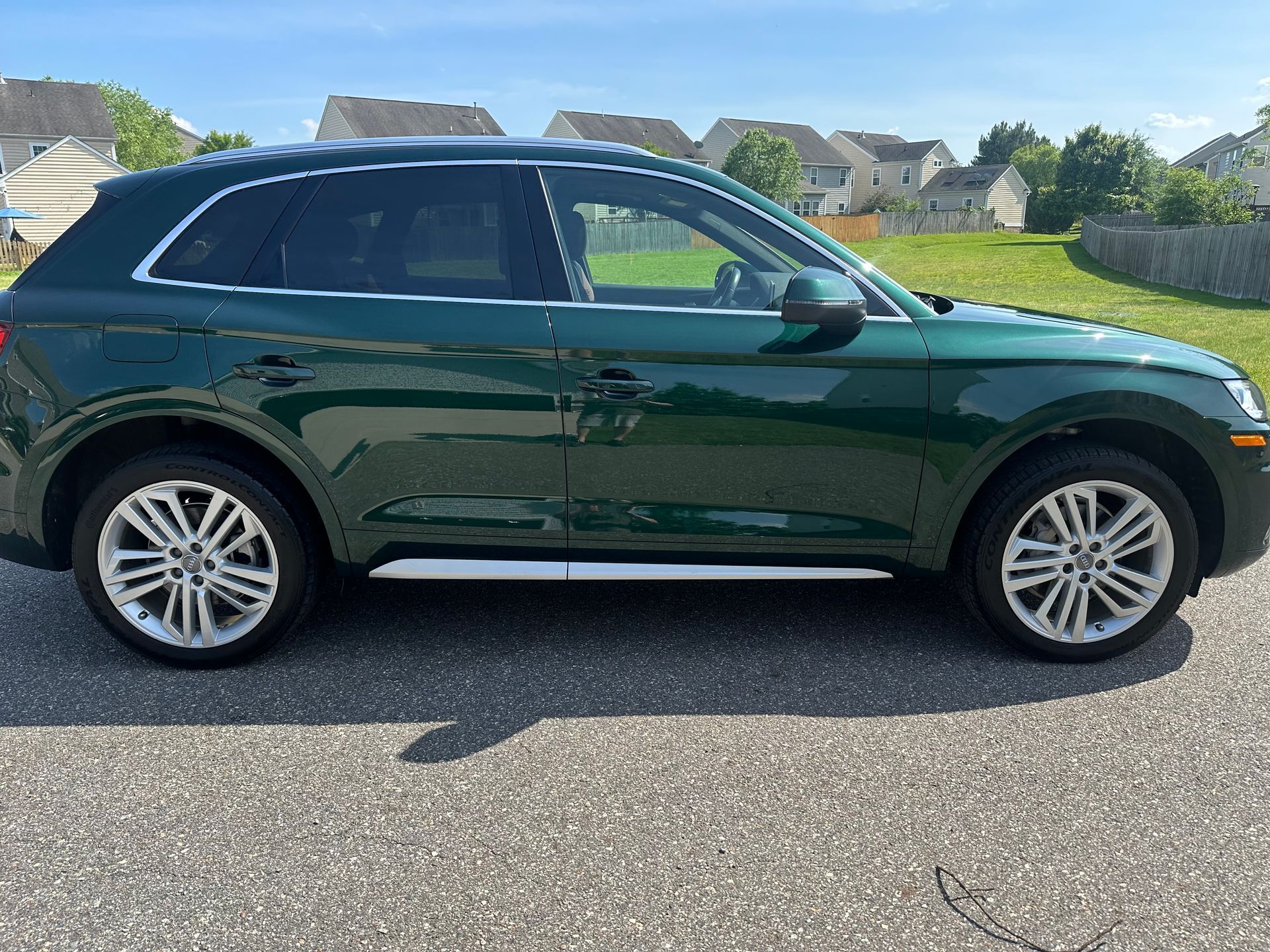 Green Audi Q5 SUV parked on asphalt in a sunny residential neighborhood.