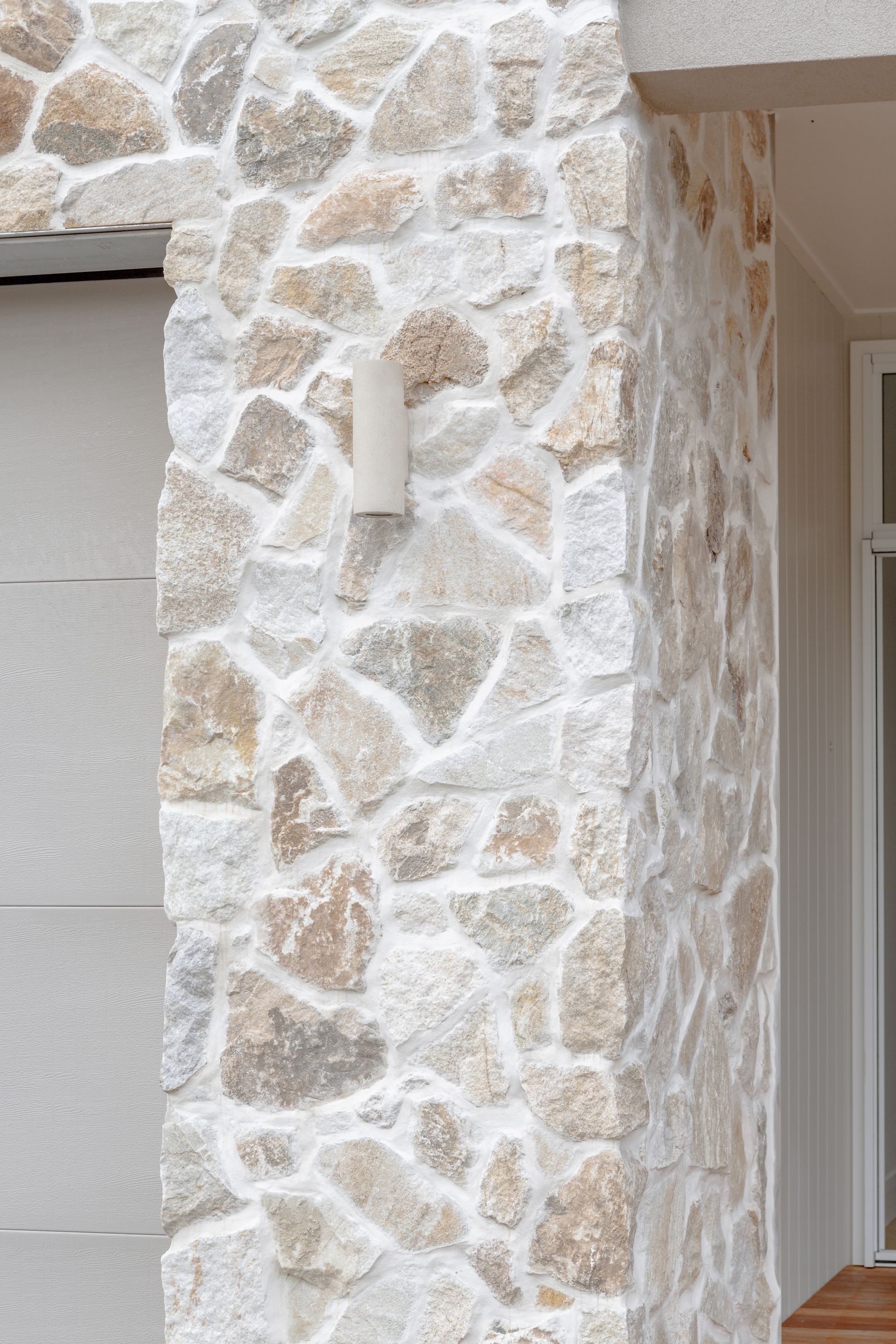 Stone wall with irregular shaped stones and white grout, exterior.