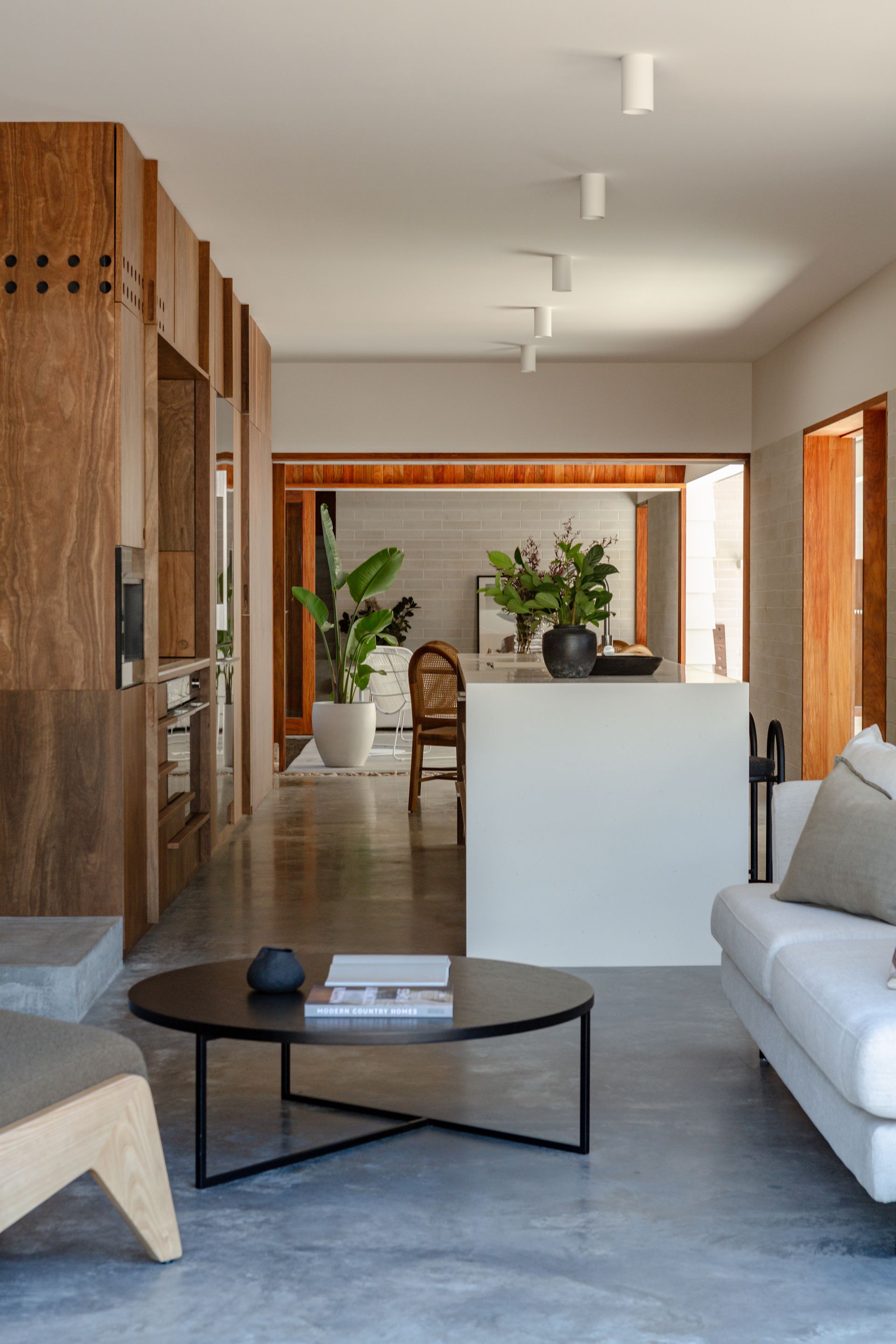 Modern living room with wood paneling, white sofa, and a black coffee table.