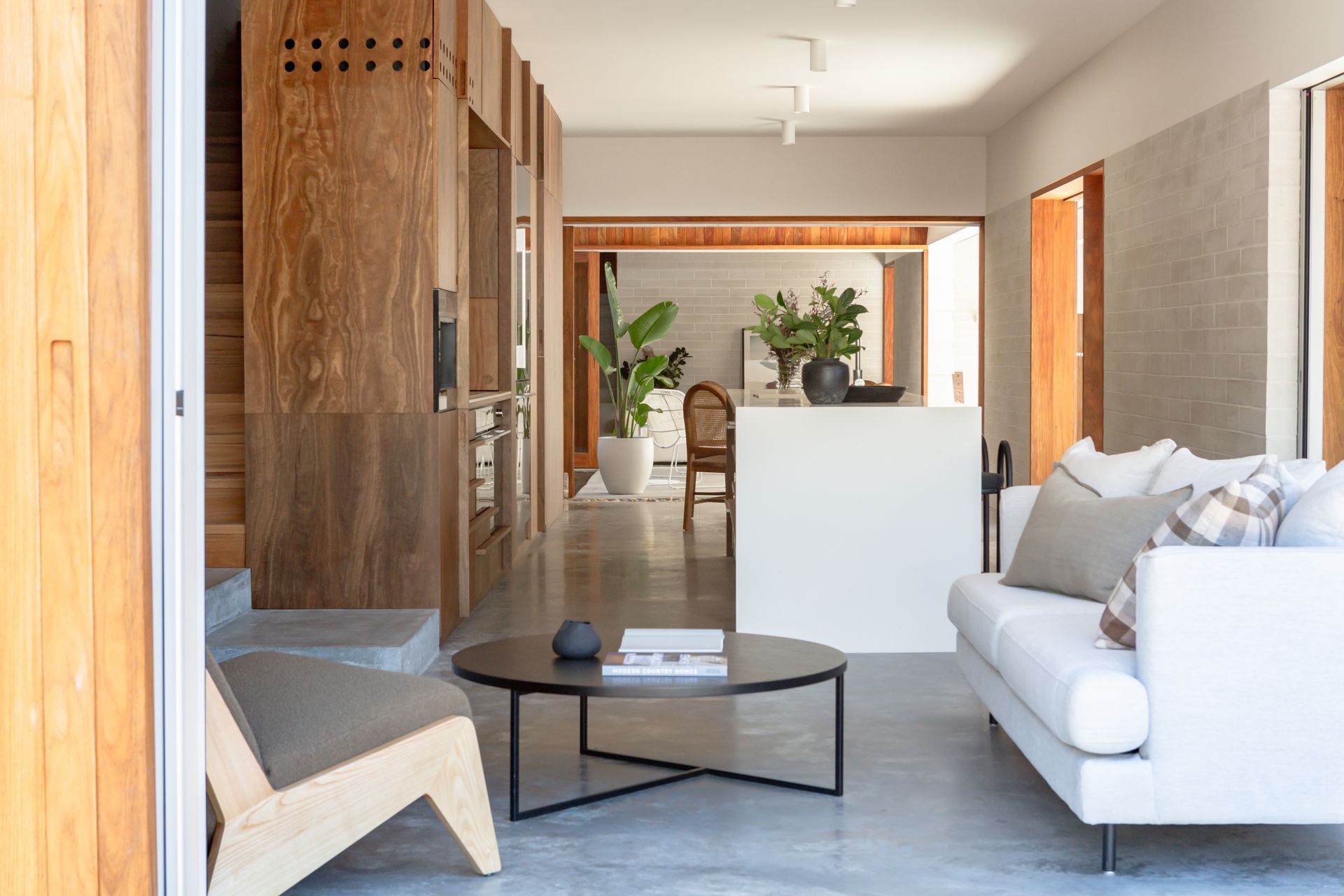 Modern living room with a white couch, round black coffee table, and wooden accents.