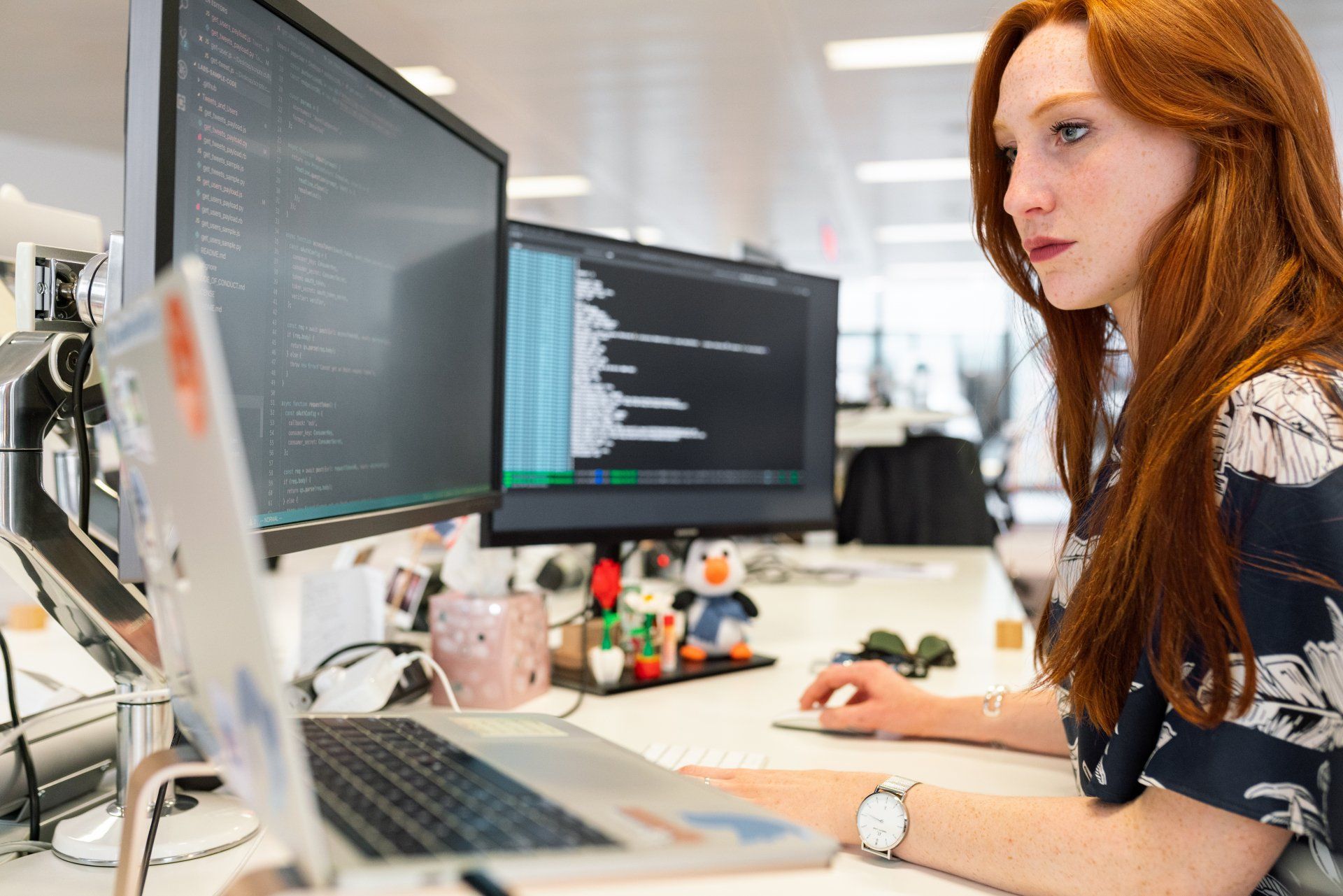 A woman is sitting at a desk working on a laptop computer.