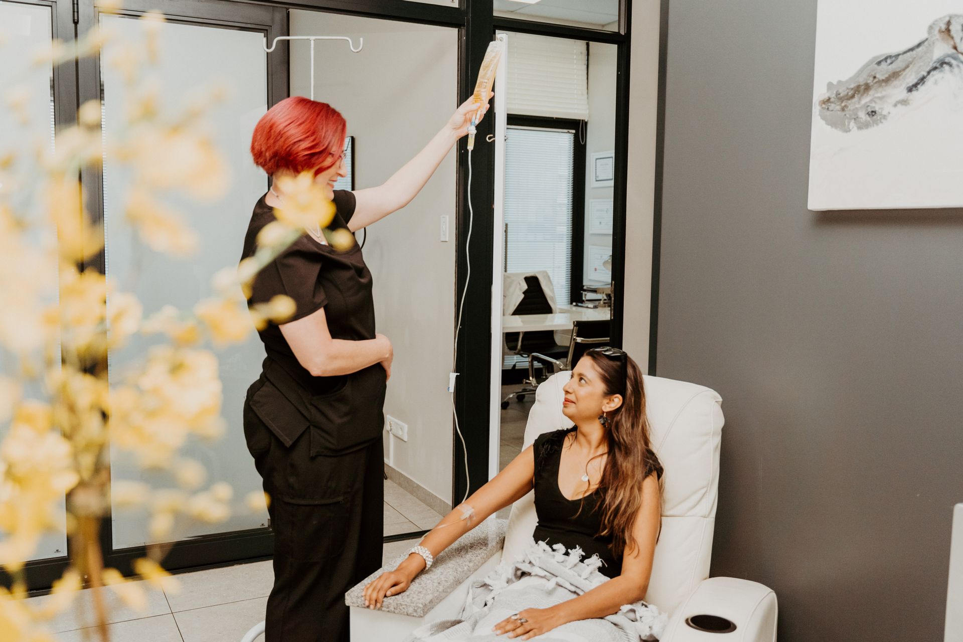 A woman is standing next to a woman sitting in a chair.