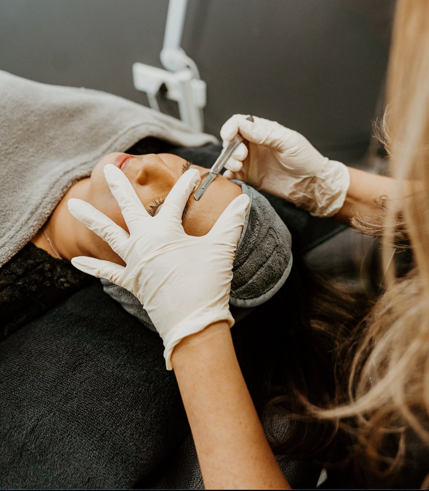 A woman is getting a facial treatment with gloves on