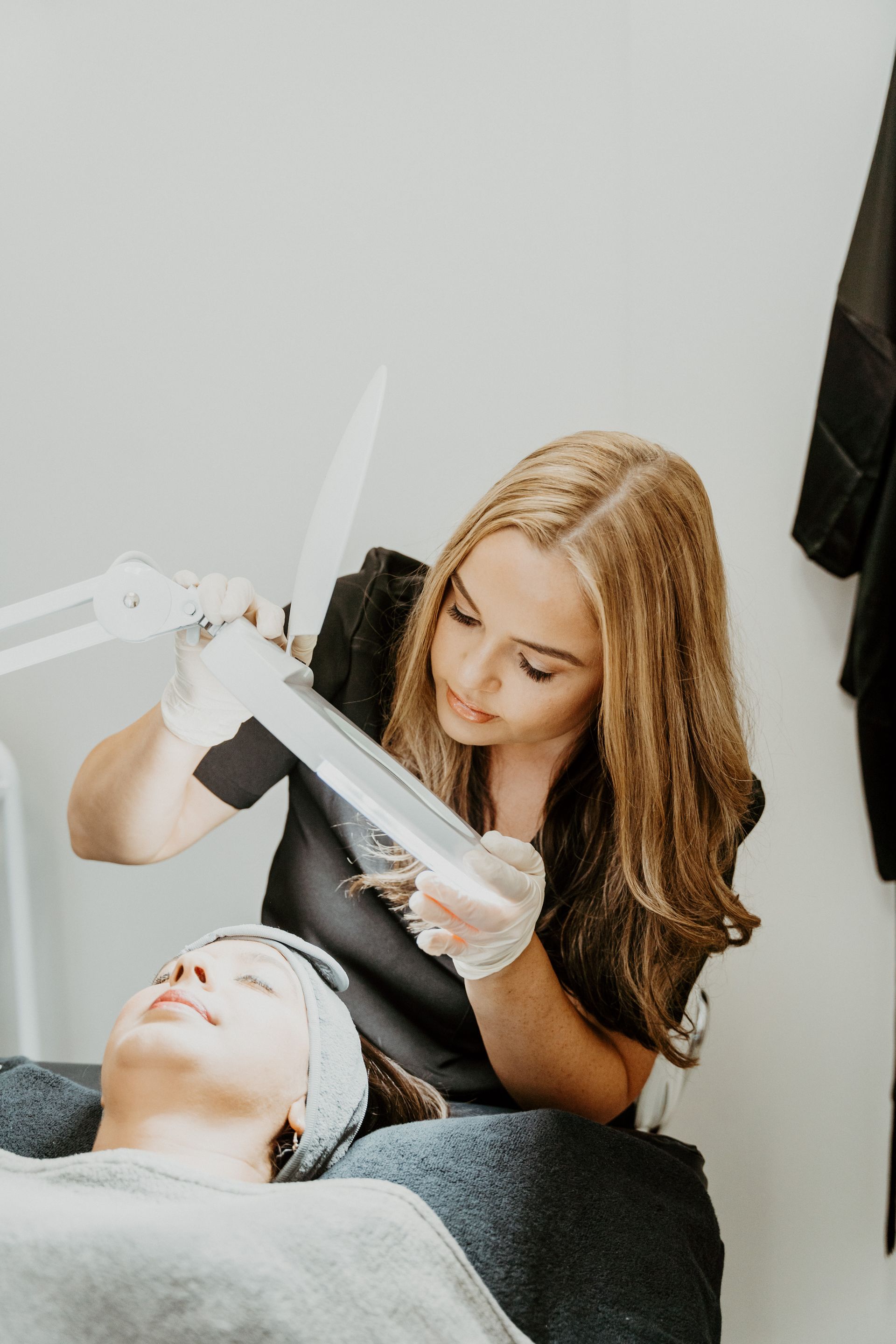A woman is examining a man 's face with a magnifying glass.
