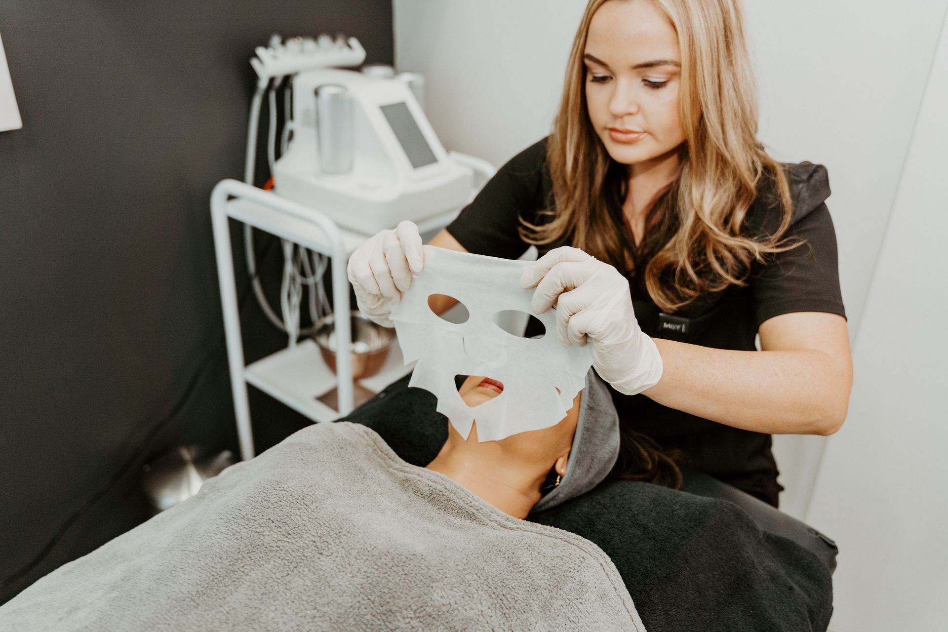 A woman is putting a mask on a man 's face.