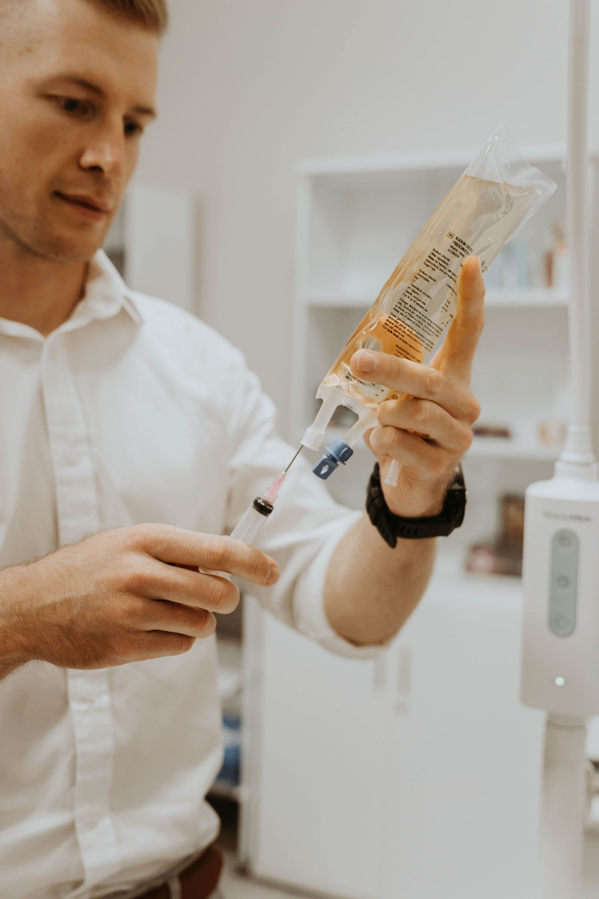 A man is holding a syringe and a bag of liquid.