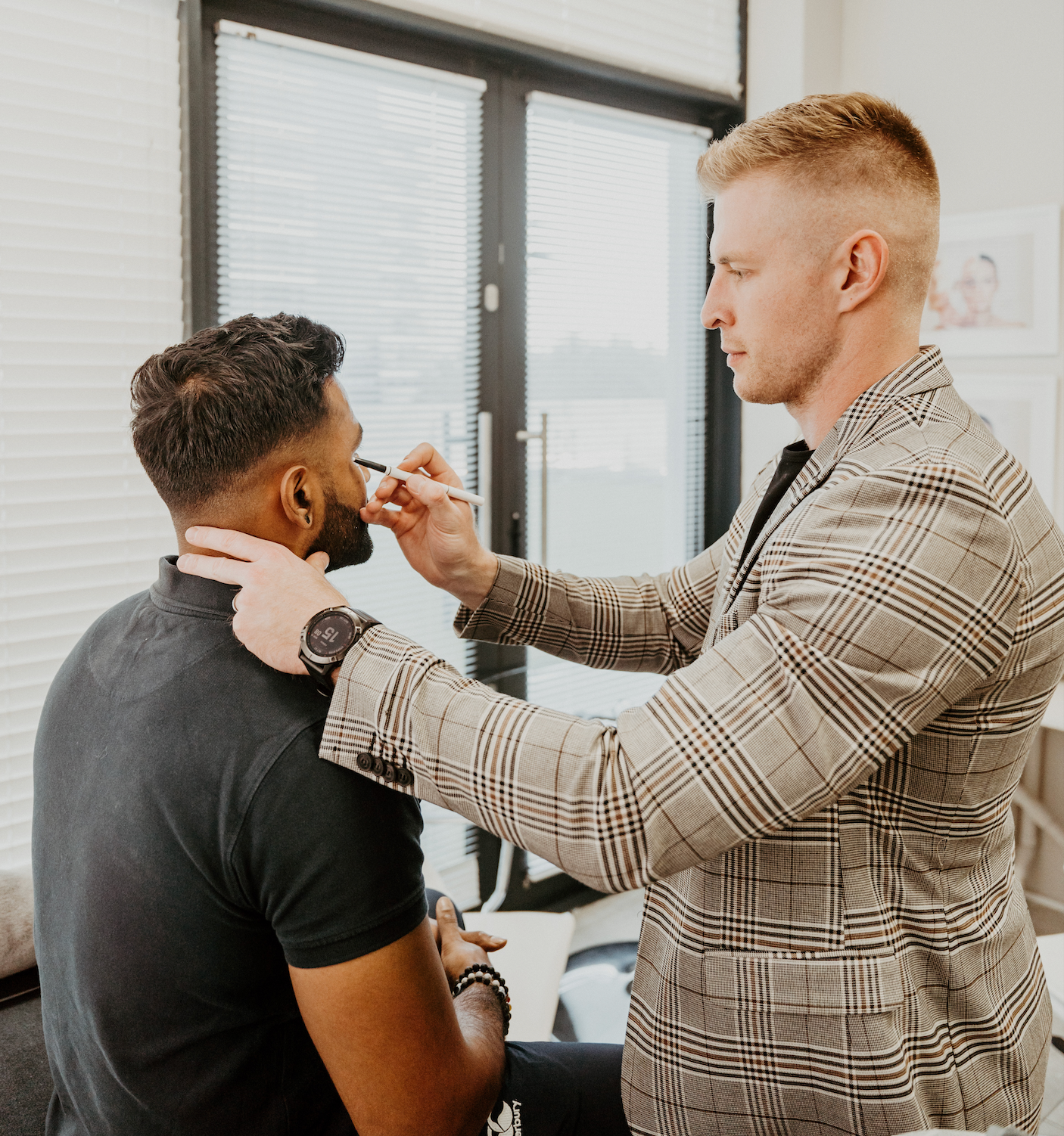 A man is applying makeup to another man 's face.