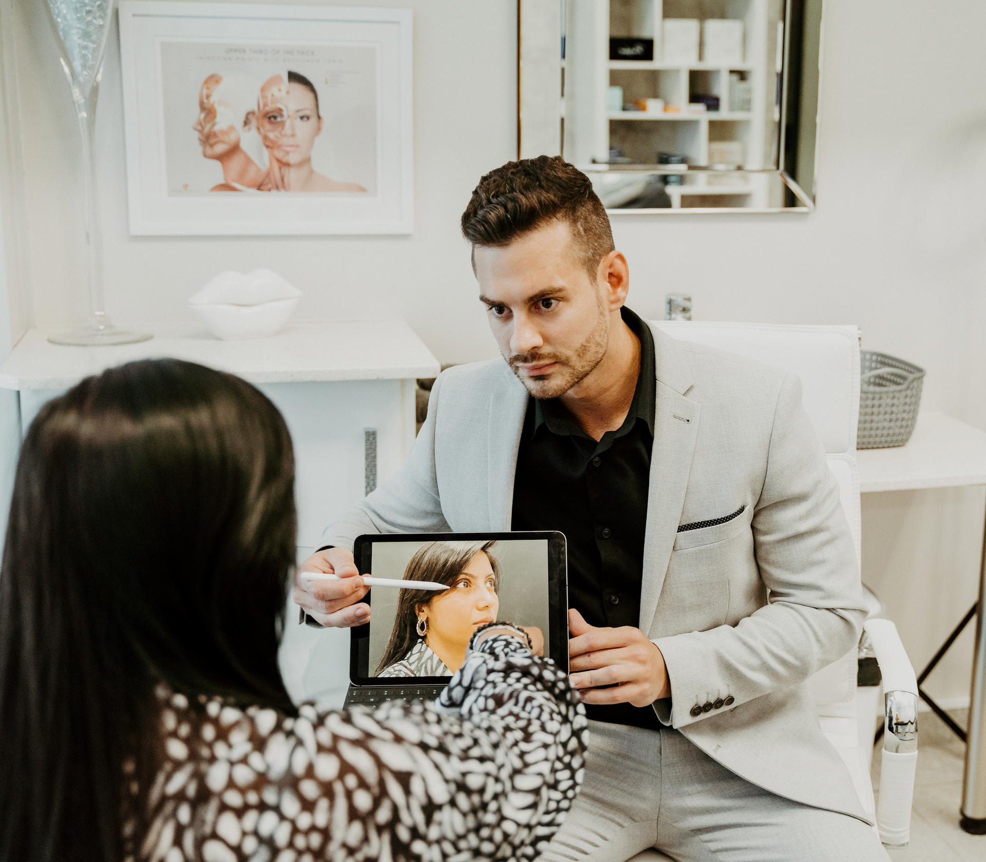 A man in a suit is talking to a woman while holding a tablet.