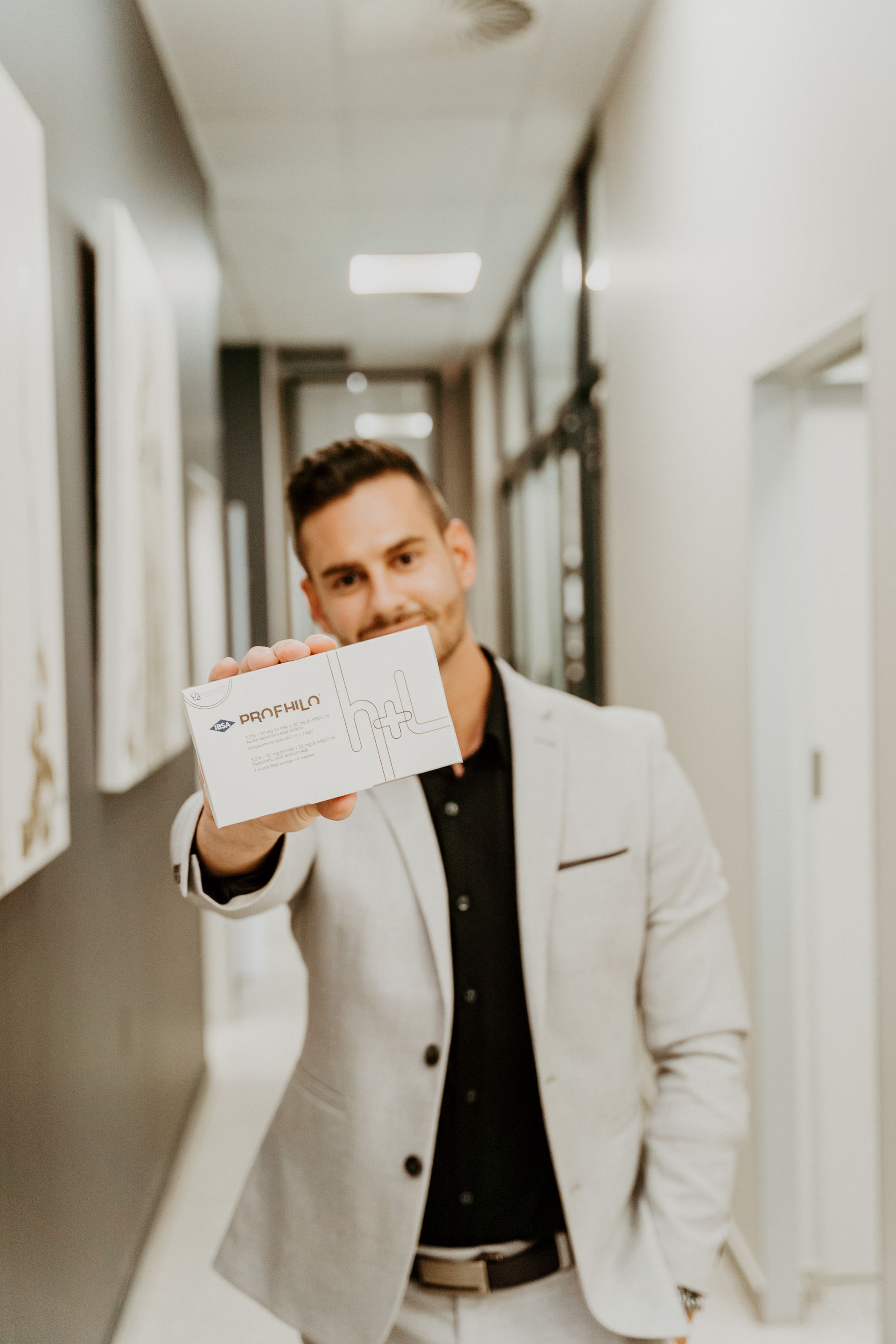 A man in a suit is holding an envelope in a hallway.