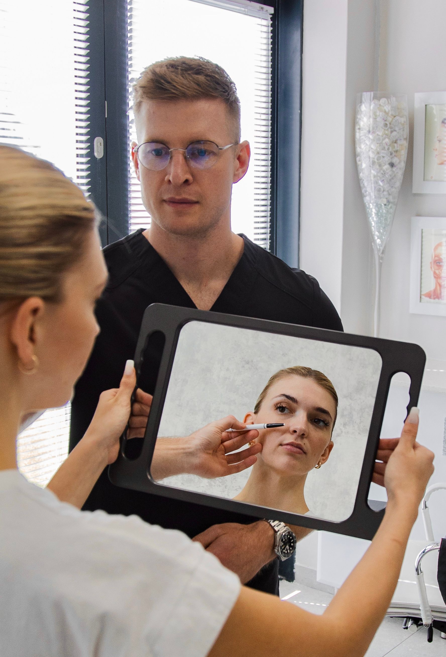 A man is looking at a woman 's face in a mirror.
