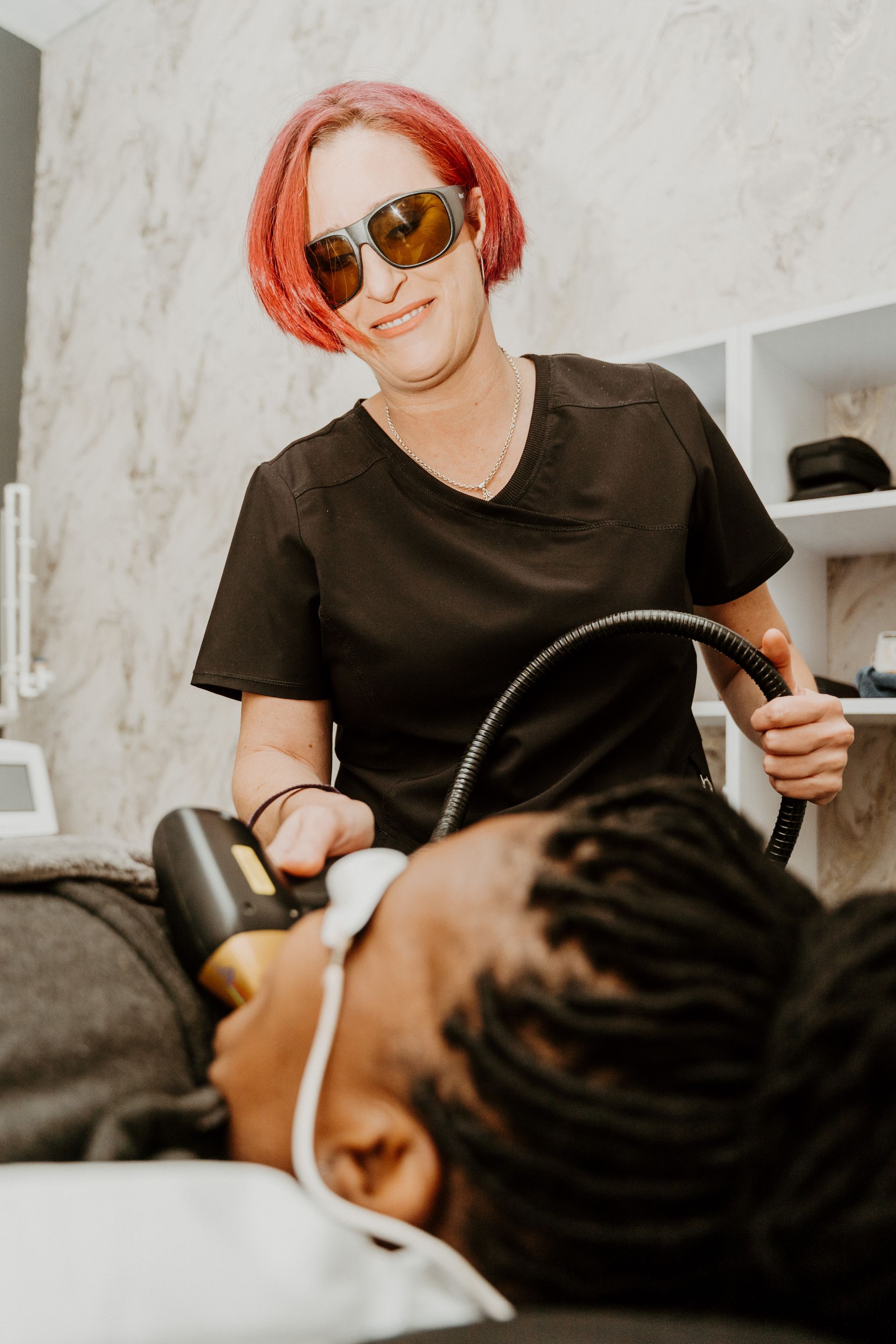 A woman is giving a man a laser treatment on his face.