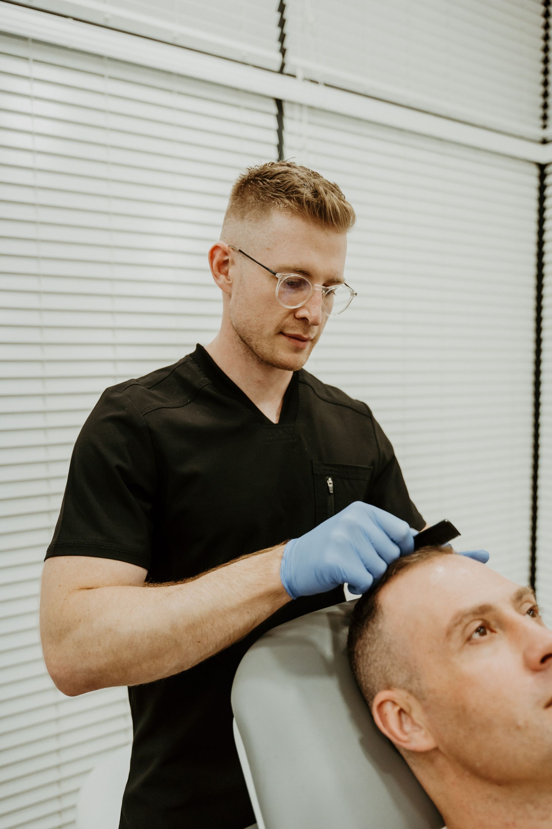 A man is getting a hair treatment from a doctor.