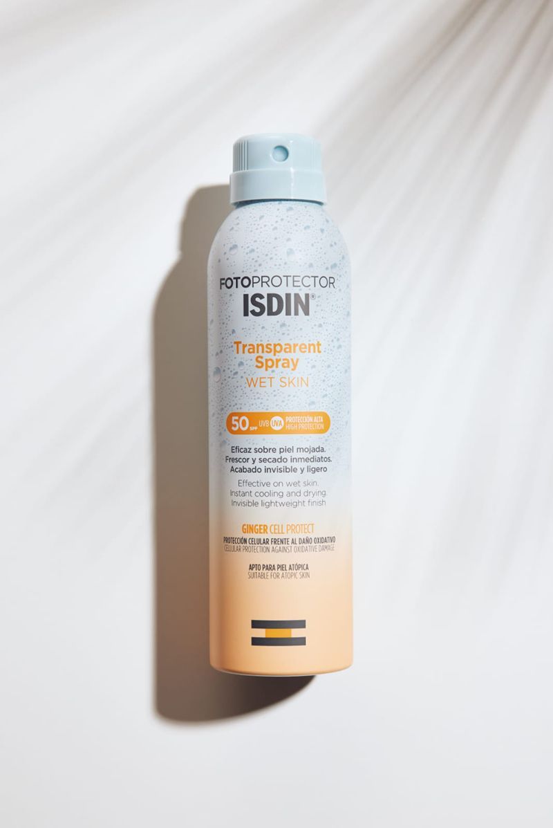 A bottle of isdin spray is sitting on a white surface