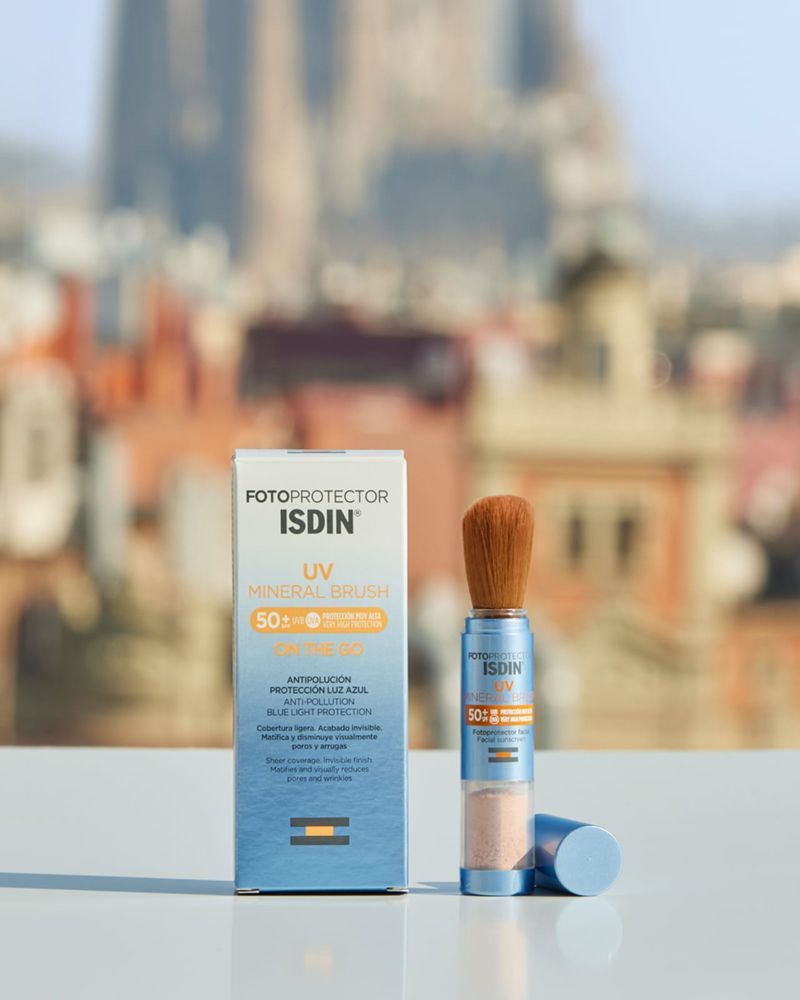 A bottle of isdin uv powder with a brush on a table.