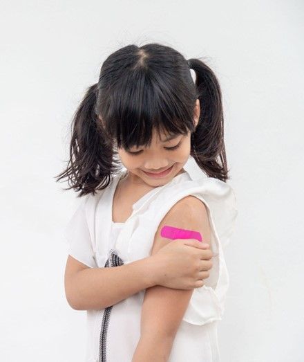 A little girl with a pink bandage on her arm.