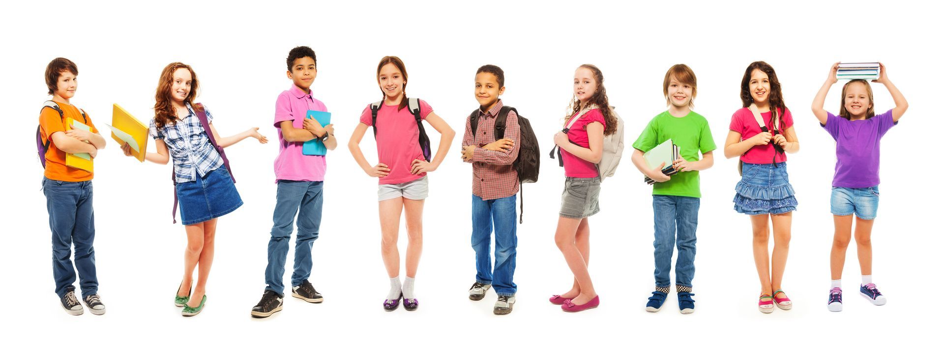 A group of children are standing in a row holding books and backpacks.