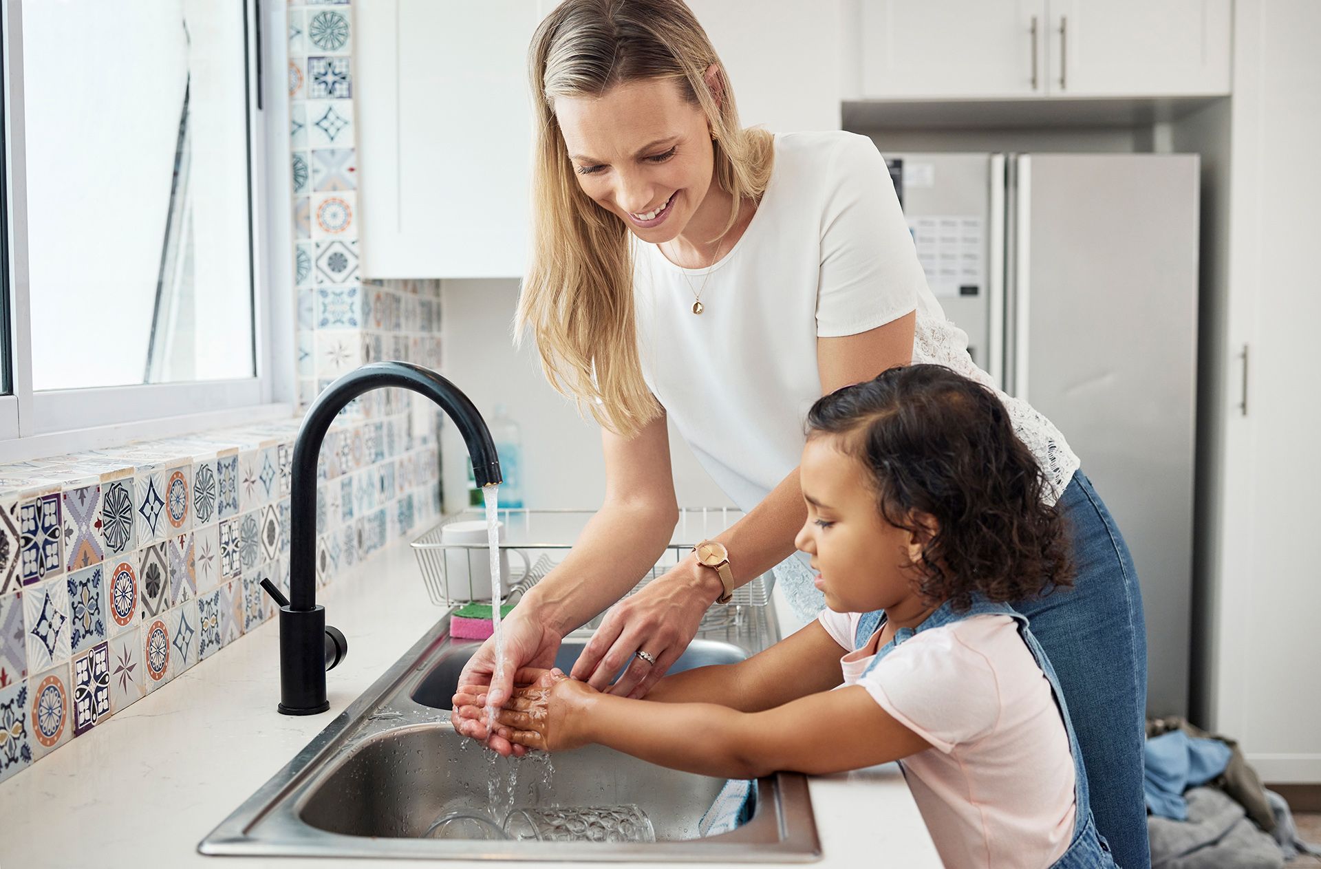 a woman helping a little girl wash her hands