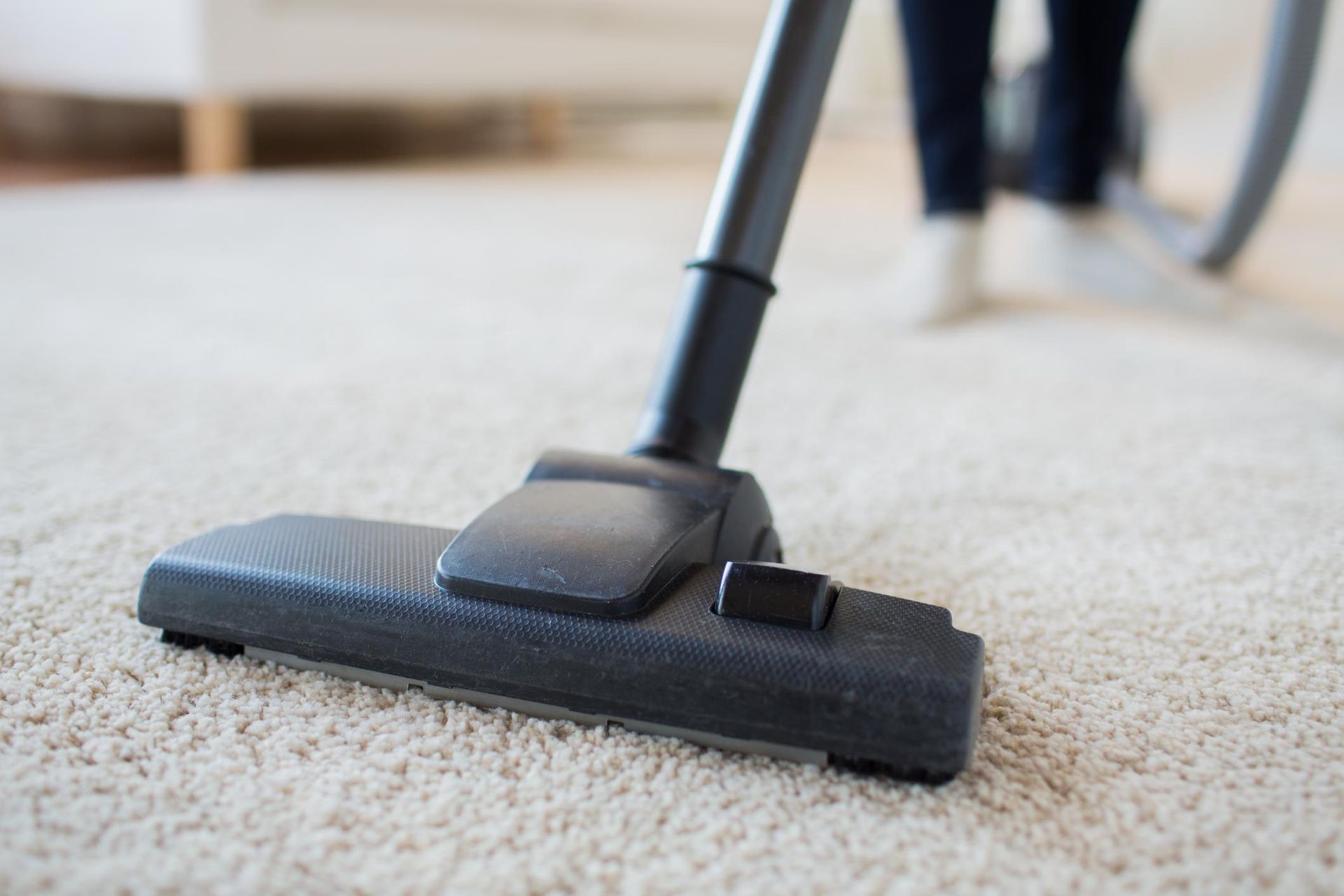 a person using a vacuum to clean a carpet