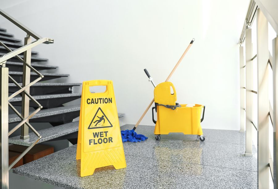 a yellow caution sign sitting on top of a counter next to a mop