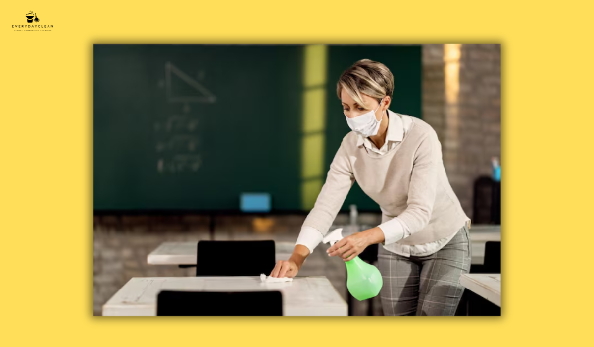 teacher cleaning classroom desk disinfectant