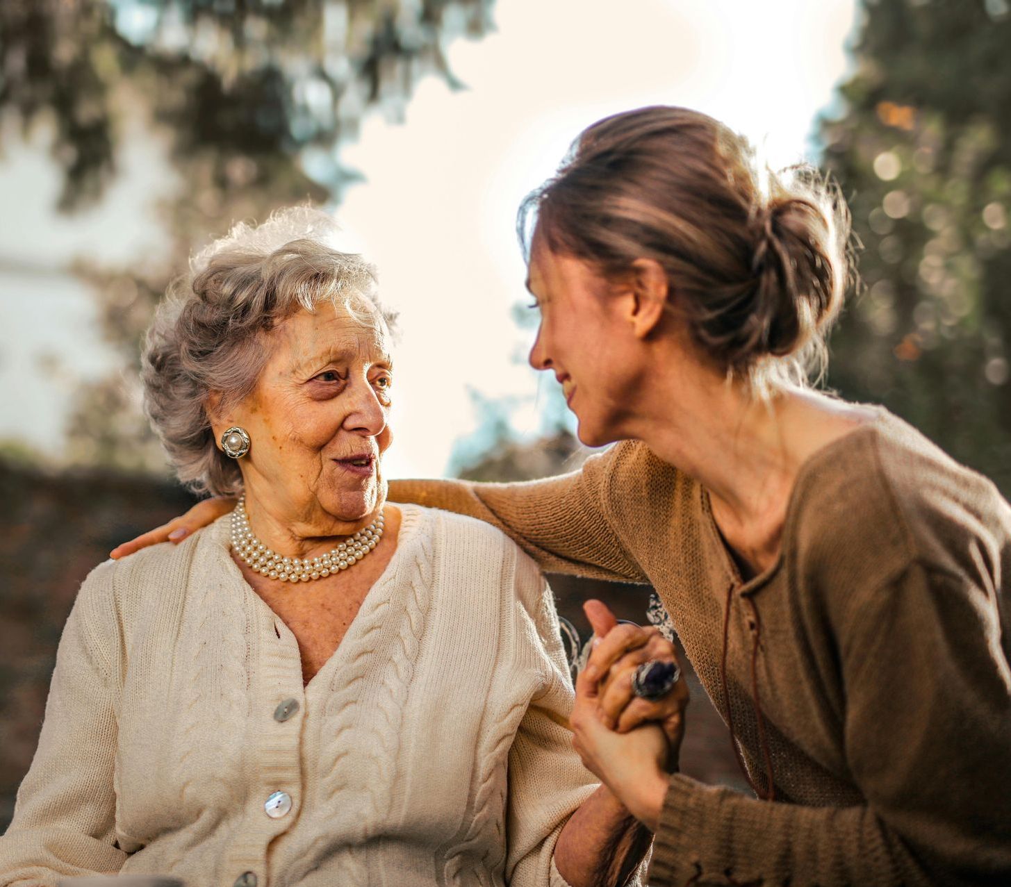 A young woman is putting her arm around an older woman 's shoulder.