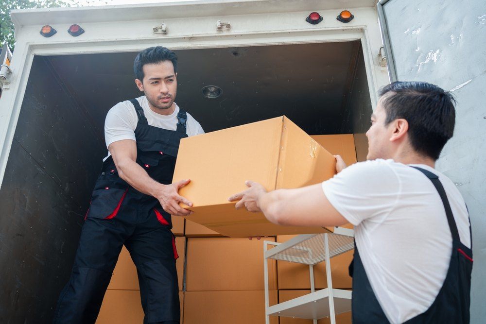 Two Men Are Carrying Boxes Out of a Truck — Buck Removals & Storage in Young, NSW